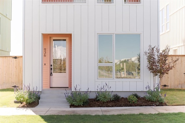 doorway to property featuring board and batten siding and fence