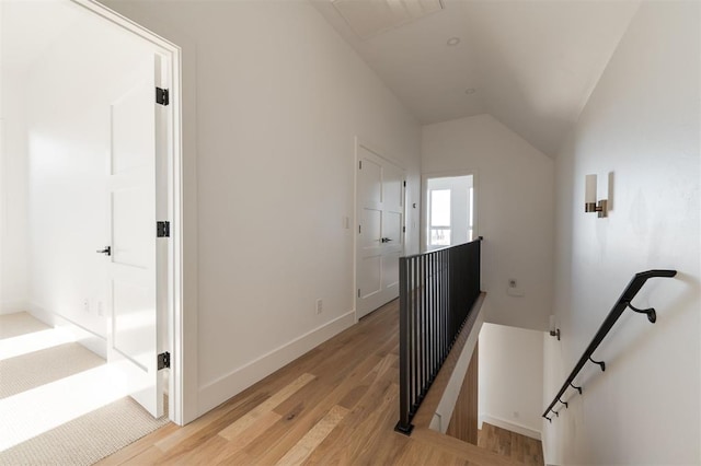 corridor featuring an upstairs landing, baseboards, light wood-style floors, and vaulted ceiling