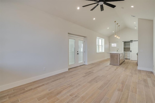 unfurnished living room with baseboards, recessed lighting, ceiling fan, light wood-style floors, and a barn door