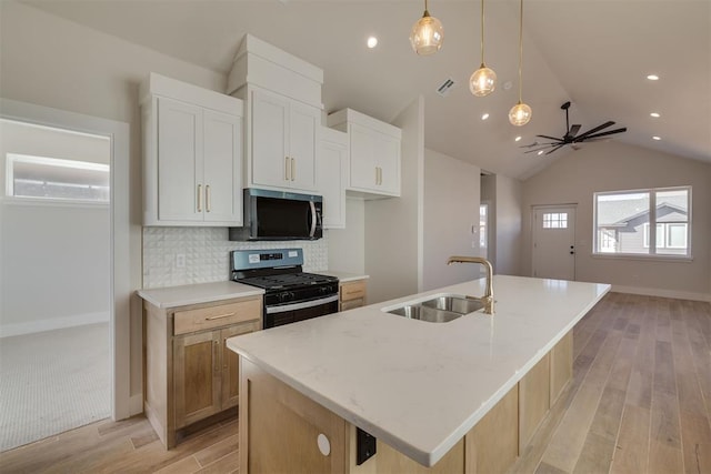 kitchen with a ceiling fan, a sink, light wood-style floors, appliances with stainless steel finishes, and decorative backsplash