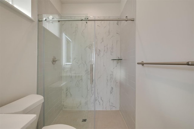 bathroom featuring a marble finish shower and toilet