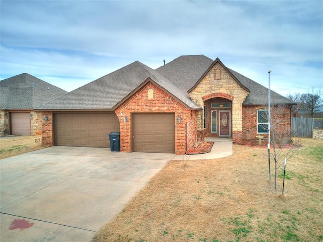 french country style house featuring brick siding, concrete driveway, a garage, and roof with shingles