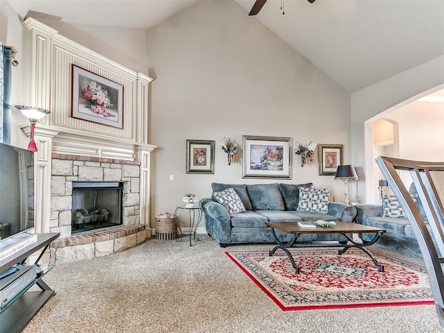 carpeted living area with a ceiling fan, baseboards, high vaulted ceiling, arched walkways, and a stone fireplace