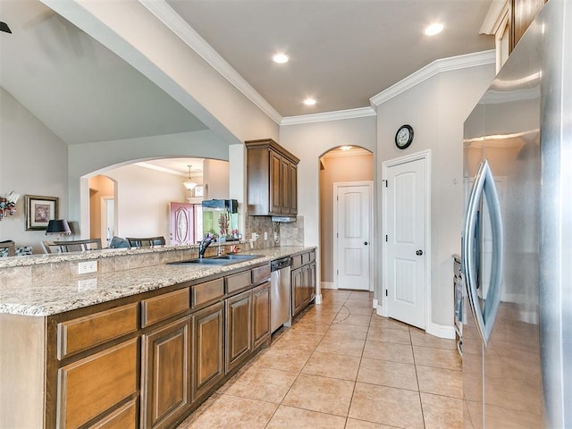 kitchen featuring ornamental molding, light tile patterned floors, appliances with stainless steel finishes, arched walkways, and a sink