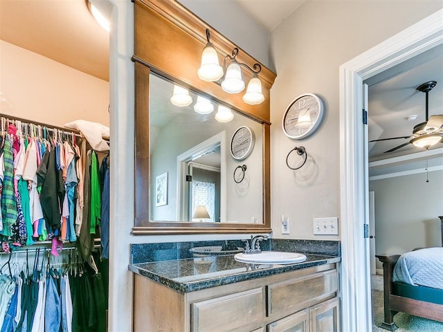 bathroom with connected bathroom, vanity, a walk in closet, and a ceiling fan