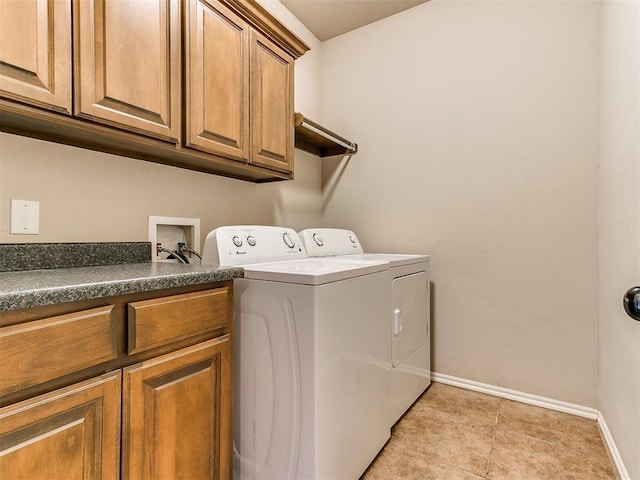 clothes washing area with cabinet space, light tile patterned floors, washer and dryer, and baseboards