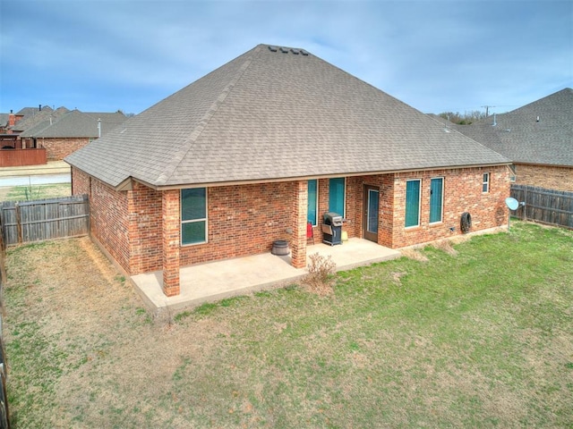 rear view of property with a patio, roof with shingles, a fenced backyard, a lawn, and brick siding