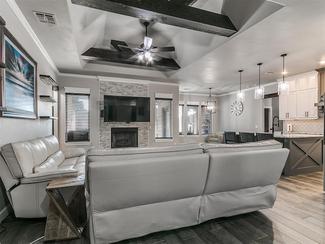 living room featuring visible vents, a healthy amount of sunlight, ornamental molding, wood finished floors, and a ceiling fan