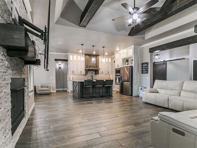 living area featuring a ceiling fan, a fireplace, crown molding, baseboards, and dark wood-style flooring