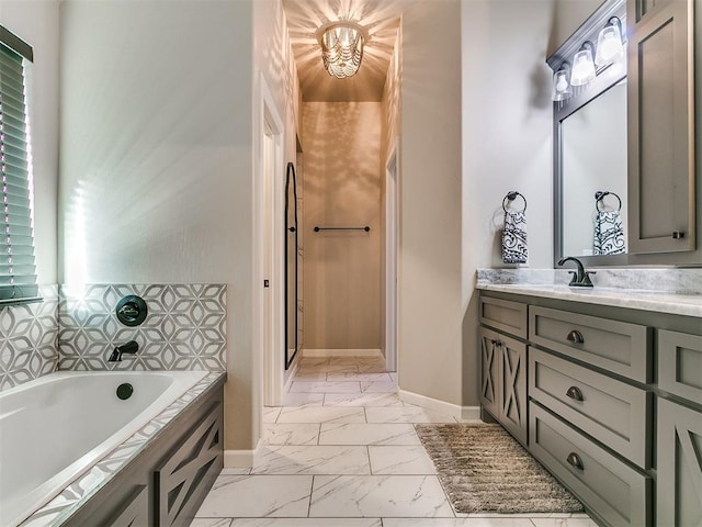 bathroom with a healthy amount of sunlight, baseboards, a bath, marble finish floor, and vanity