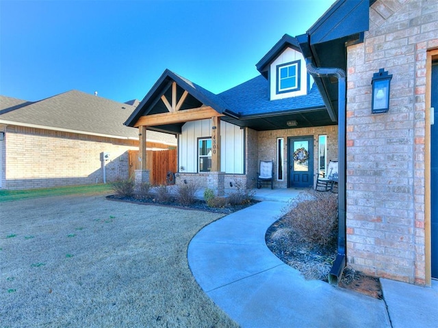 view of exterior entry featuring board and batten siding and a shingled roof