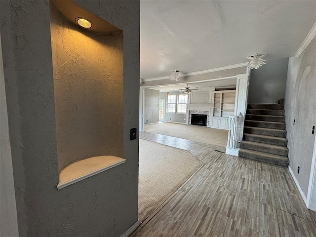 living room featuring ornamental molding, a ceiling fan, stairway, a fireplace, and a textured wall