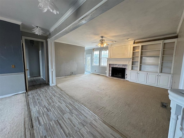 unfurnished living room with carpet, baseboards, a high end fireplace, ceiling fan, and crown molding