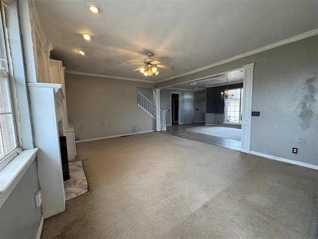 unfurnished living room with ceiling fan with notable chandelier, carpet, crown molding, a fireplace, and stairs