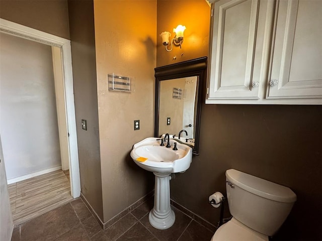 half bath featuring tile patterned floors, baseboards, and toilet