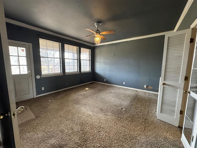 carpeted empty room featuring a wealth of natural light, baseboards, and ceiling fan