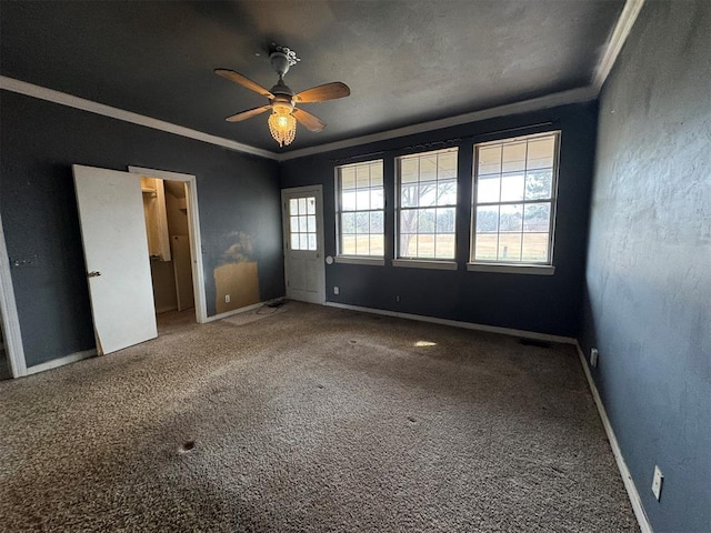 unfurnished bedroom featuring baseboards, crown molding, carpet, and a ceiling fan