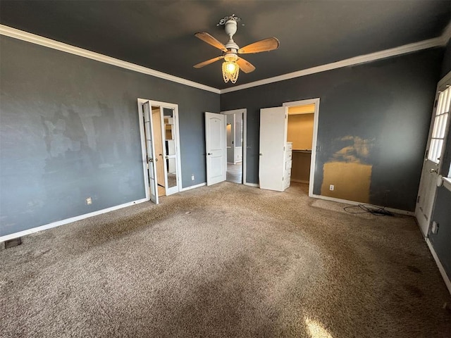 unfurnished bedroom with a closet, carpet, crown molding, baseboards, and a spacious closet