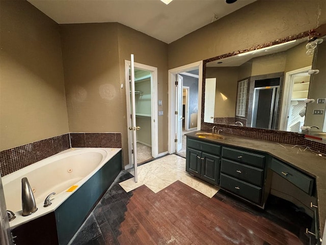 full bathroom featuring vanity, a stall shower, french doors, a walk in closet, and a jetted tub