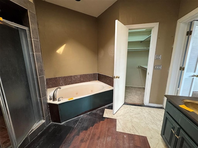 bathroom featuring a spacious closet, a jetted tub, baseboards, a stall shower, and vanity