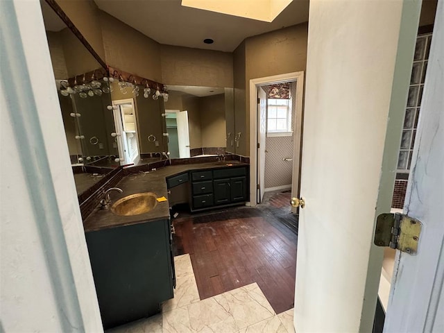 full bath with double vanity, wood finished floors, and a sink