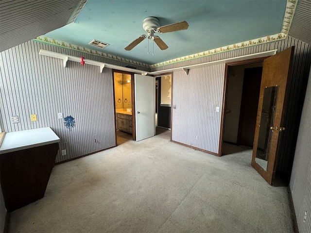 unfurnished bedroom featuring baseboards, visible vents, carpet floors, wallpapered walls, and connected bathroom