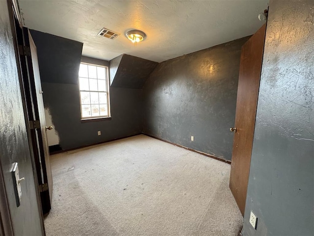 additional living space with vaulted ceiling, visible vents, carpet floors, and a textured ceiling