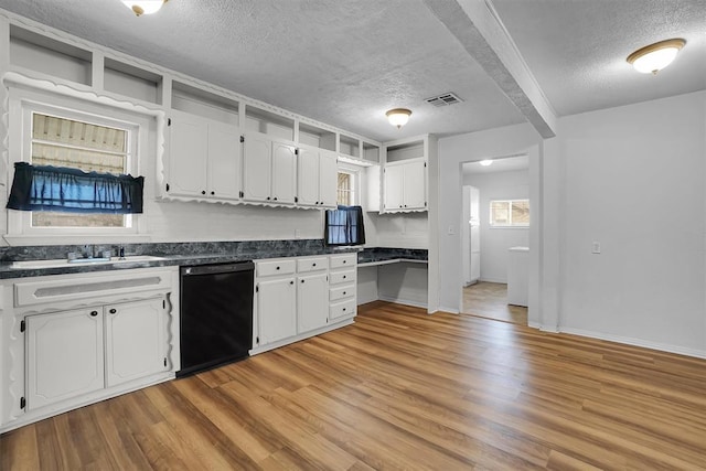 kitchen featuring dark countertops, black dishwasher, light wood-style floors, white cabinets, and a sink