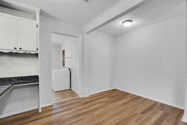 unfurnished dining area featuring washer / dryer, a textured ceiling, light wood-style flooring, and baseboards