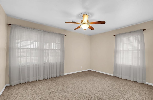 carpeted spare room featuring baseboards and a ceiling fan