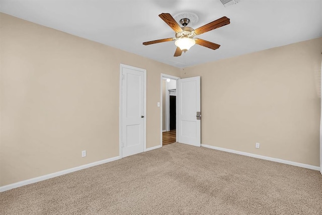 carpeted spare room featuring baseboards and ceiling fan