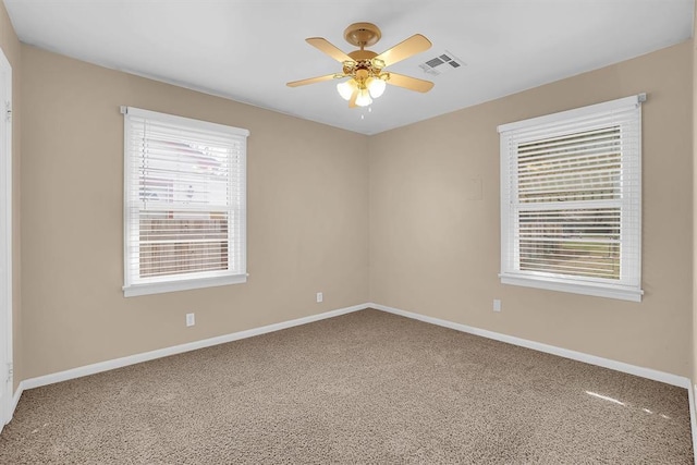 carpeted spare room featuring visible vents, baseboards, and a ceiling fan