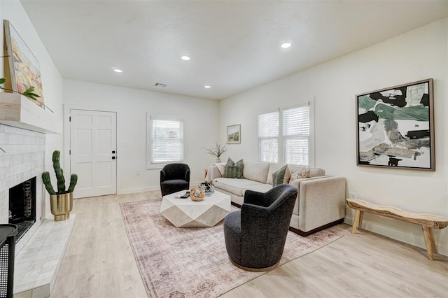 living area featuring a fireplace, recessed lighting, a healthy amount of sunlight, and light wood-type flooring