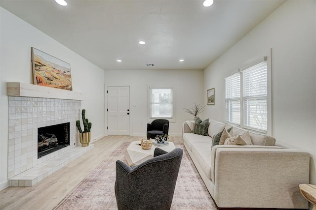 living area featuring wood finished floors, a brick fireplace, recessed lighting, and a healthy amount of sunlight