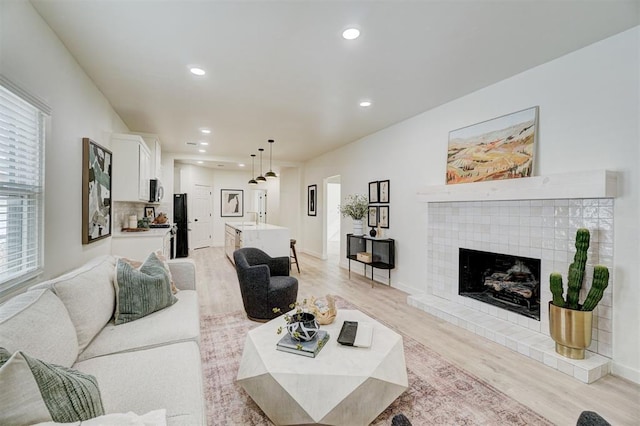 living area with recessed lighting, a fireplace, light wood-type flooring, and baseboards