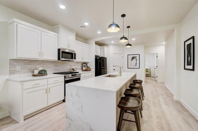 kitchen with a sink, white cabinetry, backsplash, and stainless steel appliances