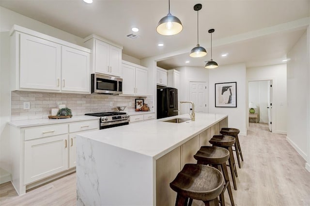 kitchen featuring visible vents, backsplash, appliances with stainless steel finishes, white cabinets, and a sink