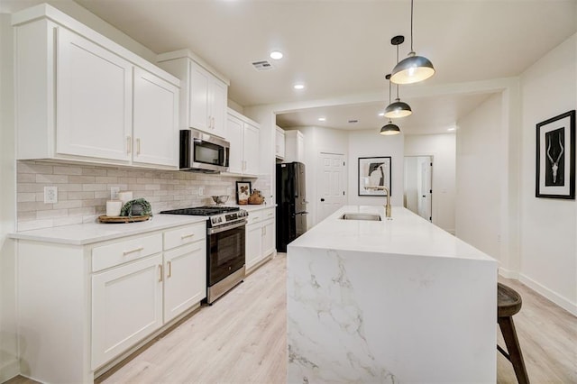 kitchen with stainless steel appliances, backsplash, visible vents, and white cabinets