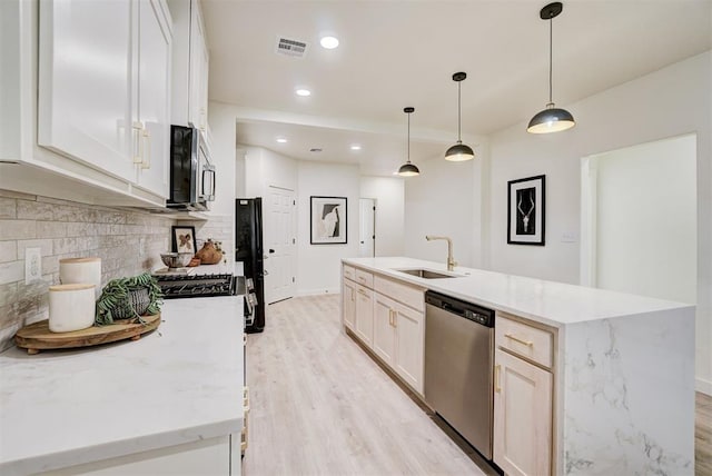 kitchen with visible vents, a sink, appliances with stainless steel finishes, light wood finished floors, and decorative backsplash