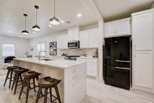 kitchen featuring visible vents, backsplash, appliances with stainless steel finishes, white cabinets, and a sink