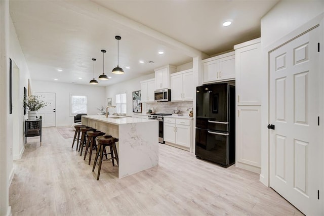 kitchen featuring backsplash, appliances with stainless steel finishes, white cabinetry, and a sink