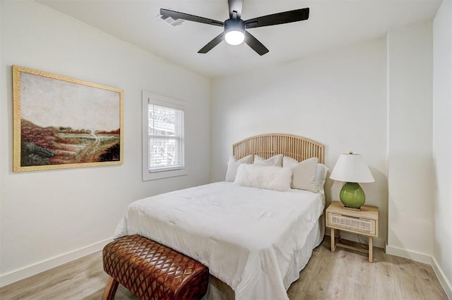 bedroom with visible vents, baseboards, light wood finished floors, and ceiling fan