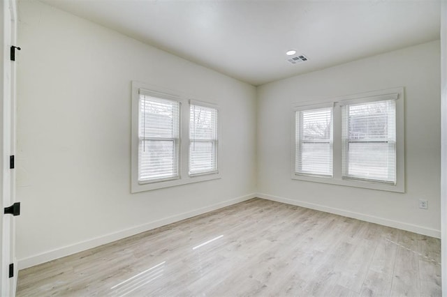 empty room with visible vents, light wood-style floors, and baseboards