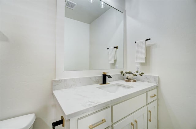 bathroom featuring visible vents, toilet, and vanity