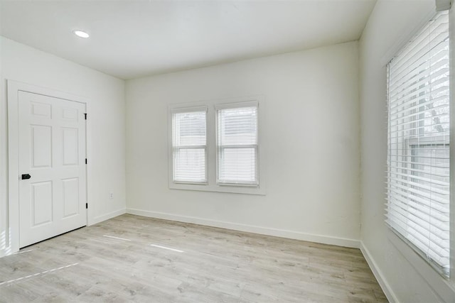 empty room featuring baseboards, a wealth of natural light, and light wood-type flooring