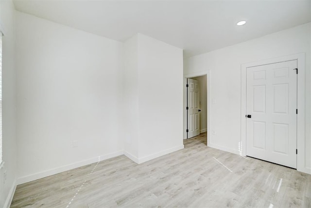 empty room featuring recessed lighting, baseboards, and light wood-type flooring