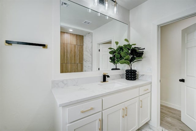 bathroom featuring visible vents, vanity, baseboards, and wood finished floors