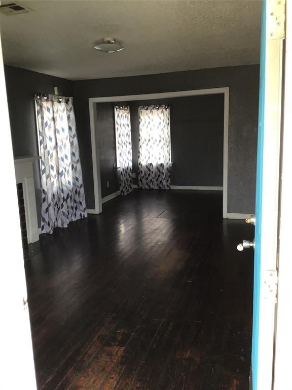 empty room with visible vents, baseboards, and wood finished floors