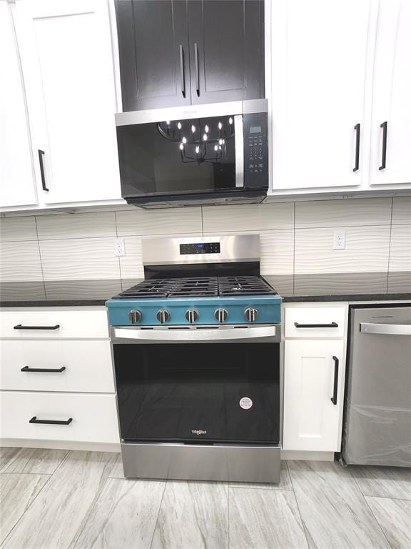 11613 NW 103rd St, Yukon, OK 73099 - kitchen featuring stainless steel appliances, white cabinets, tasteful backsplash, and dark countertops