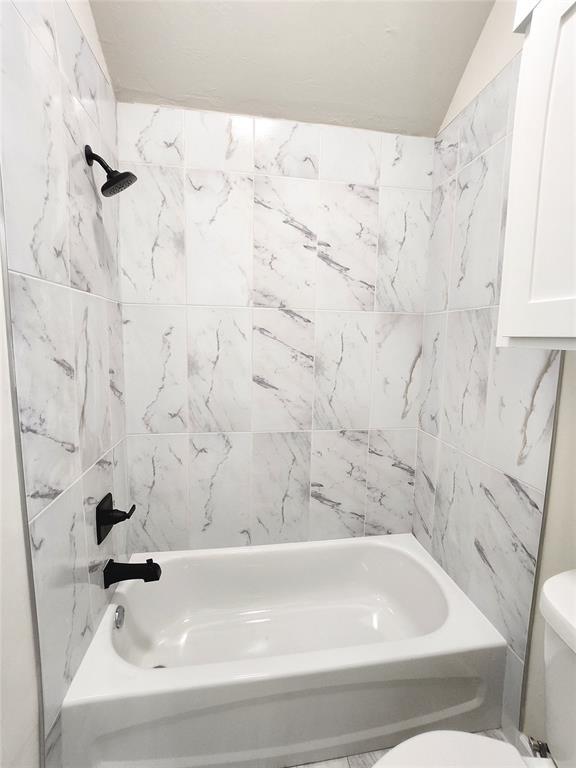 11613 NW 103rd St, Yukon, OK 73099 - full bathroom featuring toilet, shower / washtub combination, and lofted ceiling